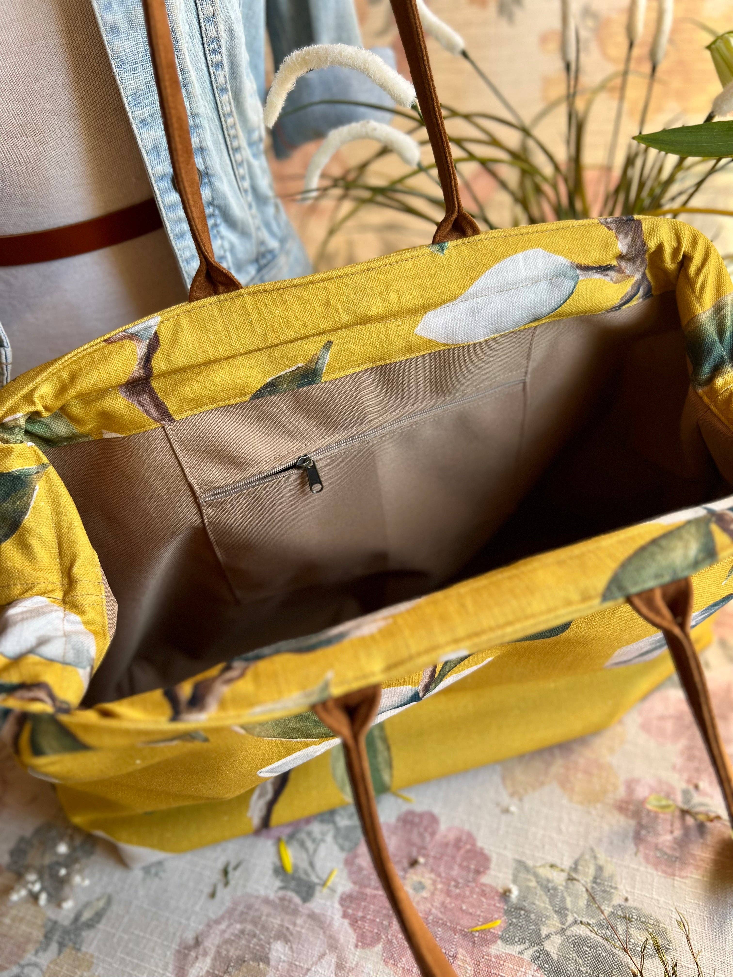 Yellow floral-patterned tote bag with a brown interior on a floral surface.