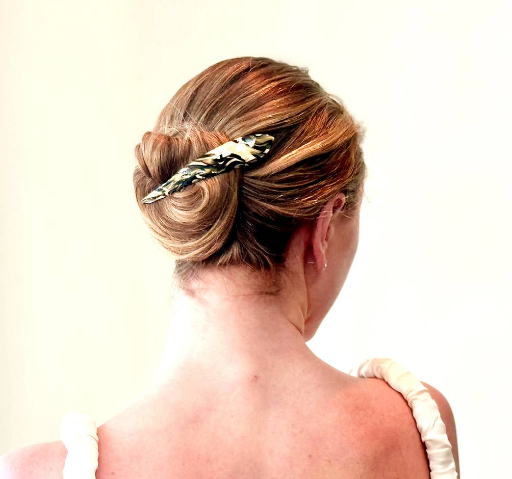 Woman with a stylish hair bun adorned with a decorative hair accessory on a plain background