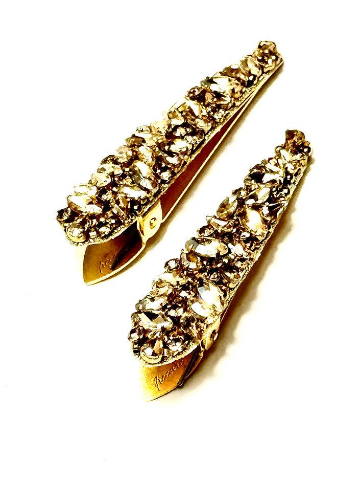 Gold hair clips with crystal embellishments on a white background