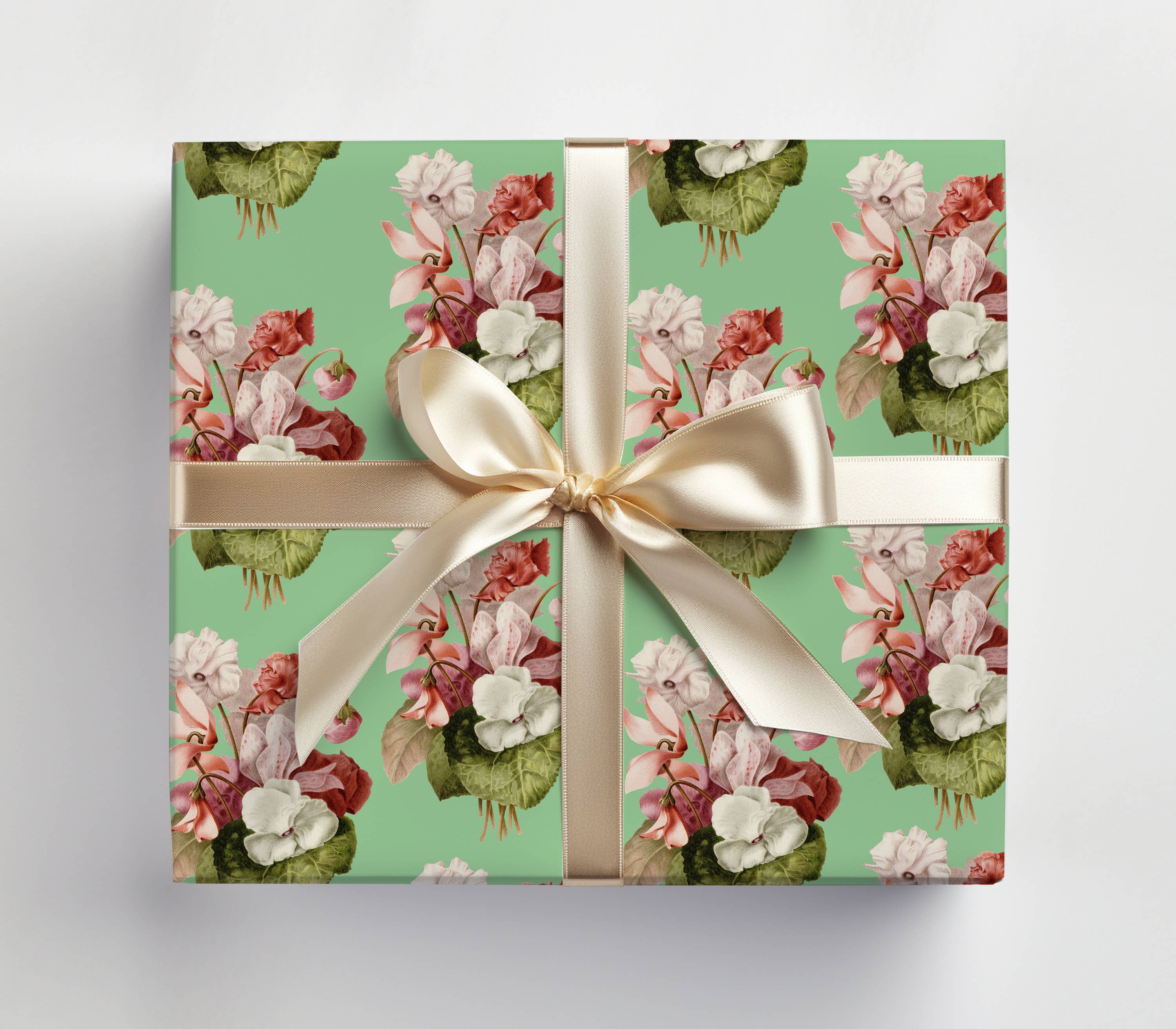 Gift box with floral pattern and white ribbon on a light gray background