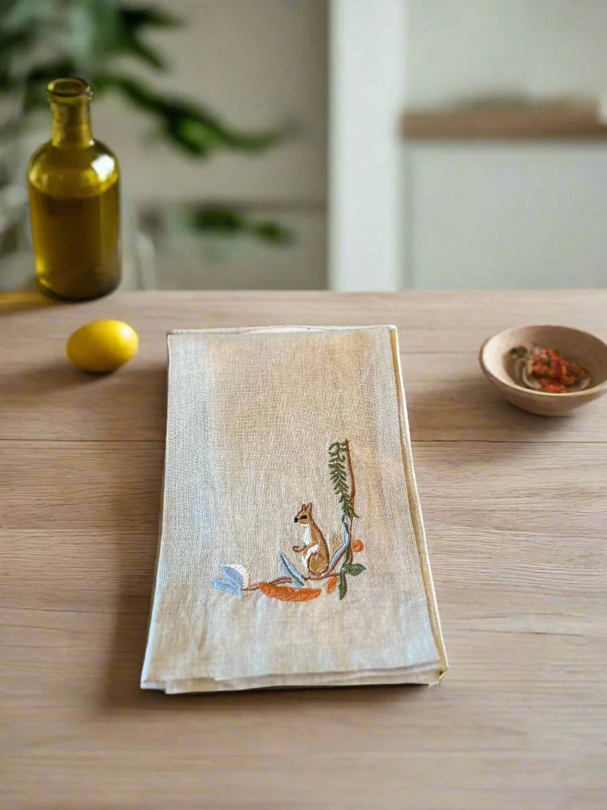 Embroidered napkin with a squirrel design on a wooden table