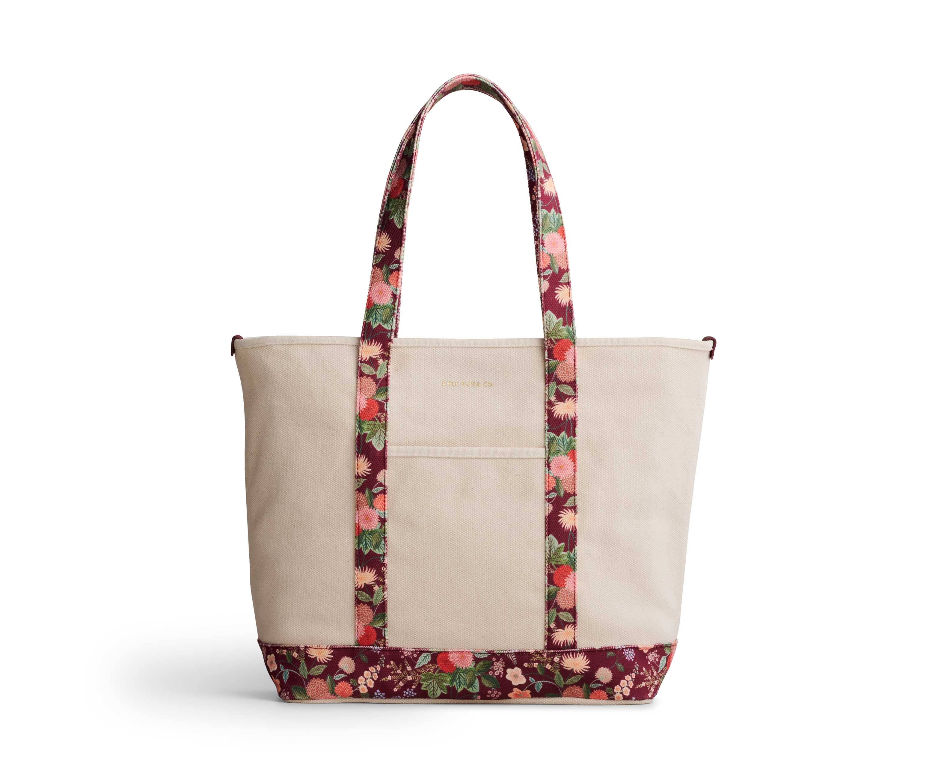 Beige tote bag with floral patterned handle and bottom edge on a white background