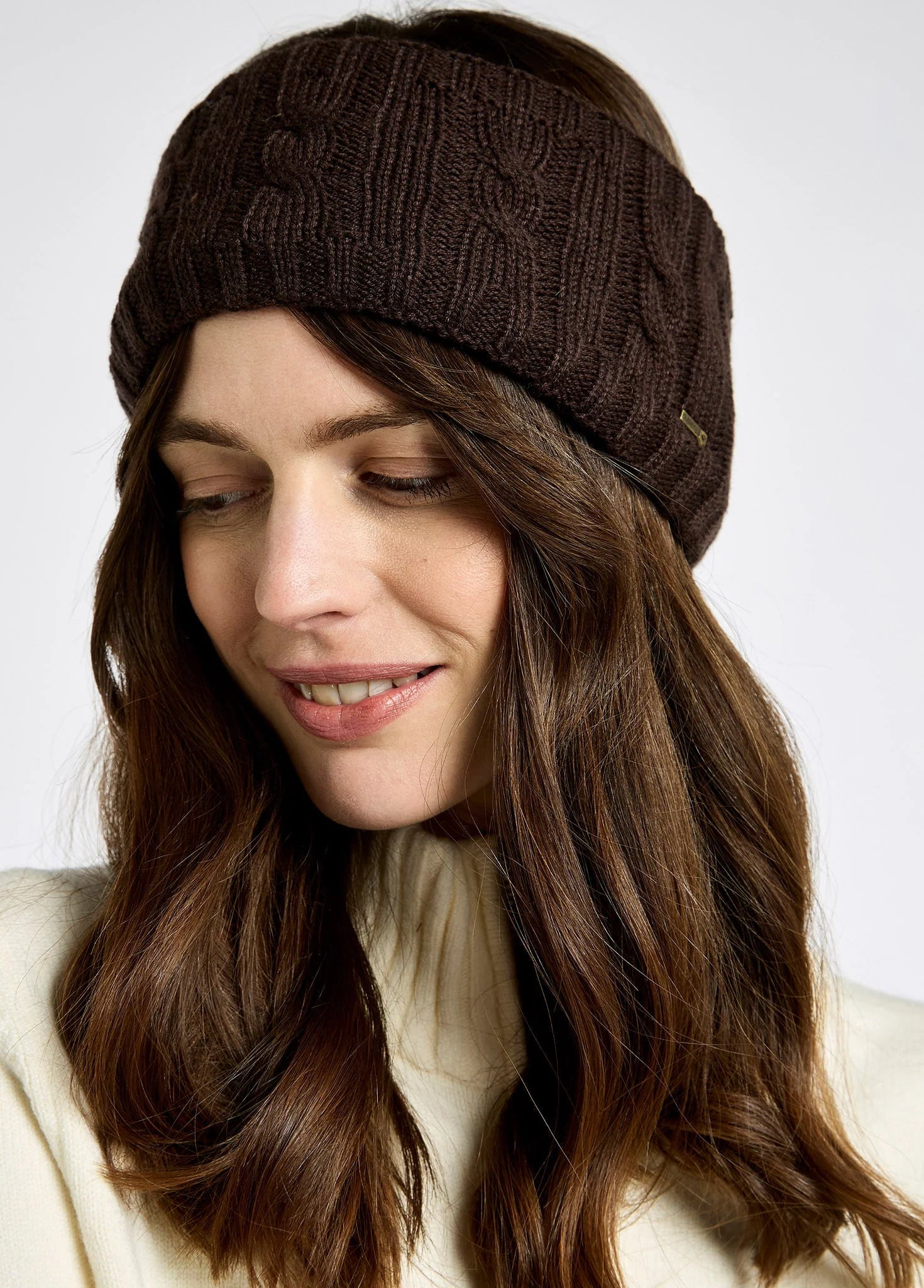Woman wearing a brown knitted headband against a white background