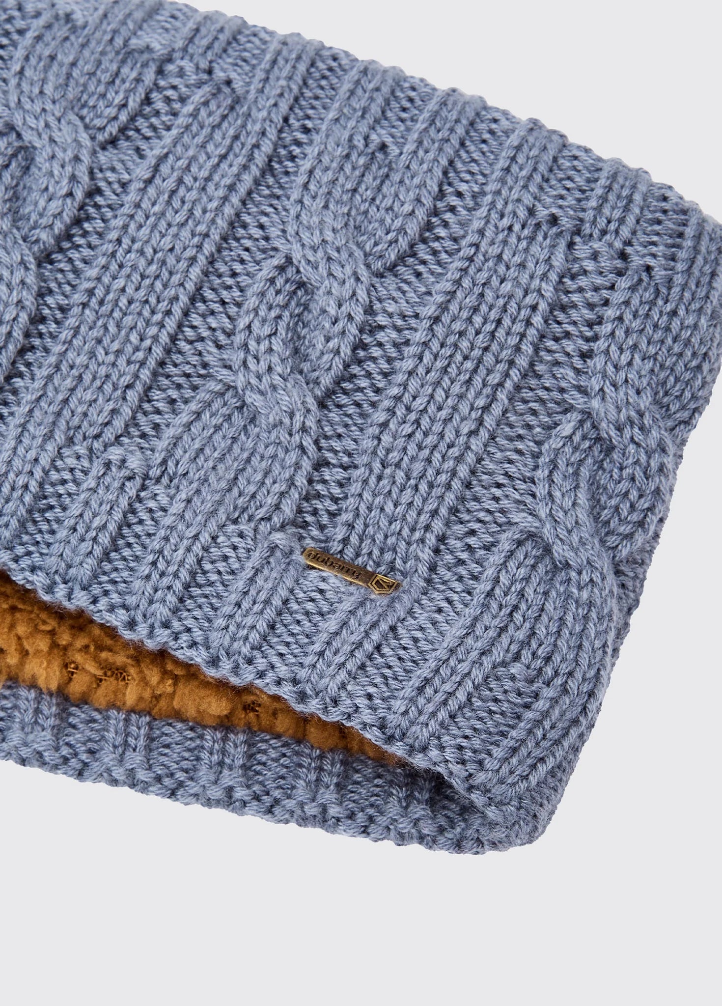 Blue knitted beanie with brown interior on a light gray background