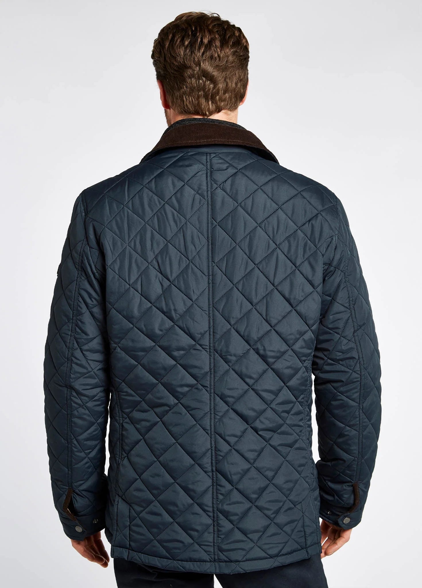 Man wearing a quilted navy jacket on a white background