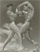 Black and white photograph of two nude men in a dynamic pose against a cloudy sky.