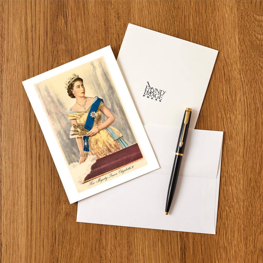 Greeting card with portrait of a woman, envelope, and pen on a wooden surface