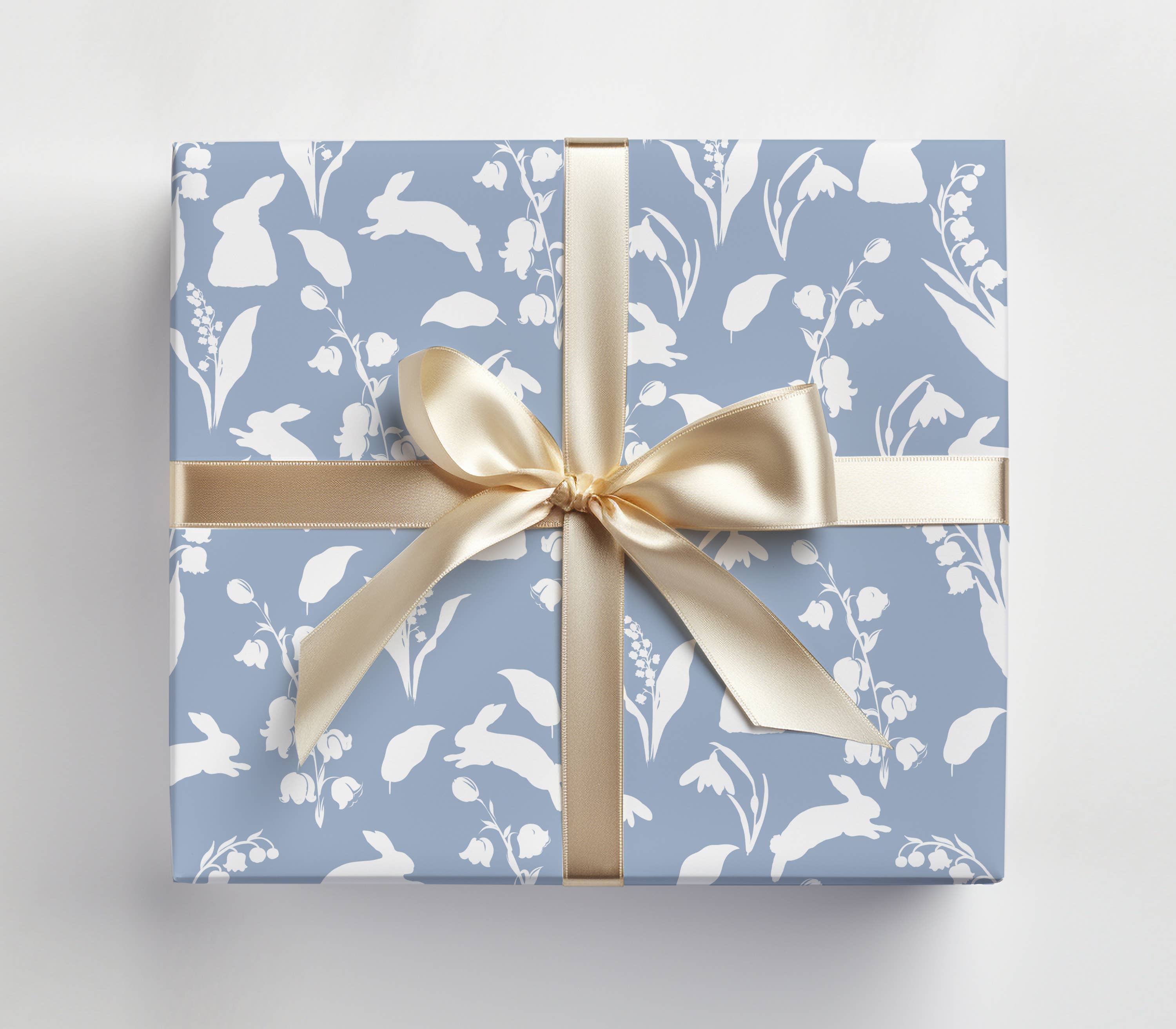 Gift box with floral pattern and gold ribbon on a light gray background