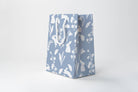 Blue paper bag with white floral and leaf pattern on a white background