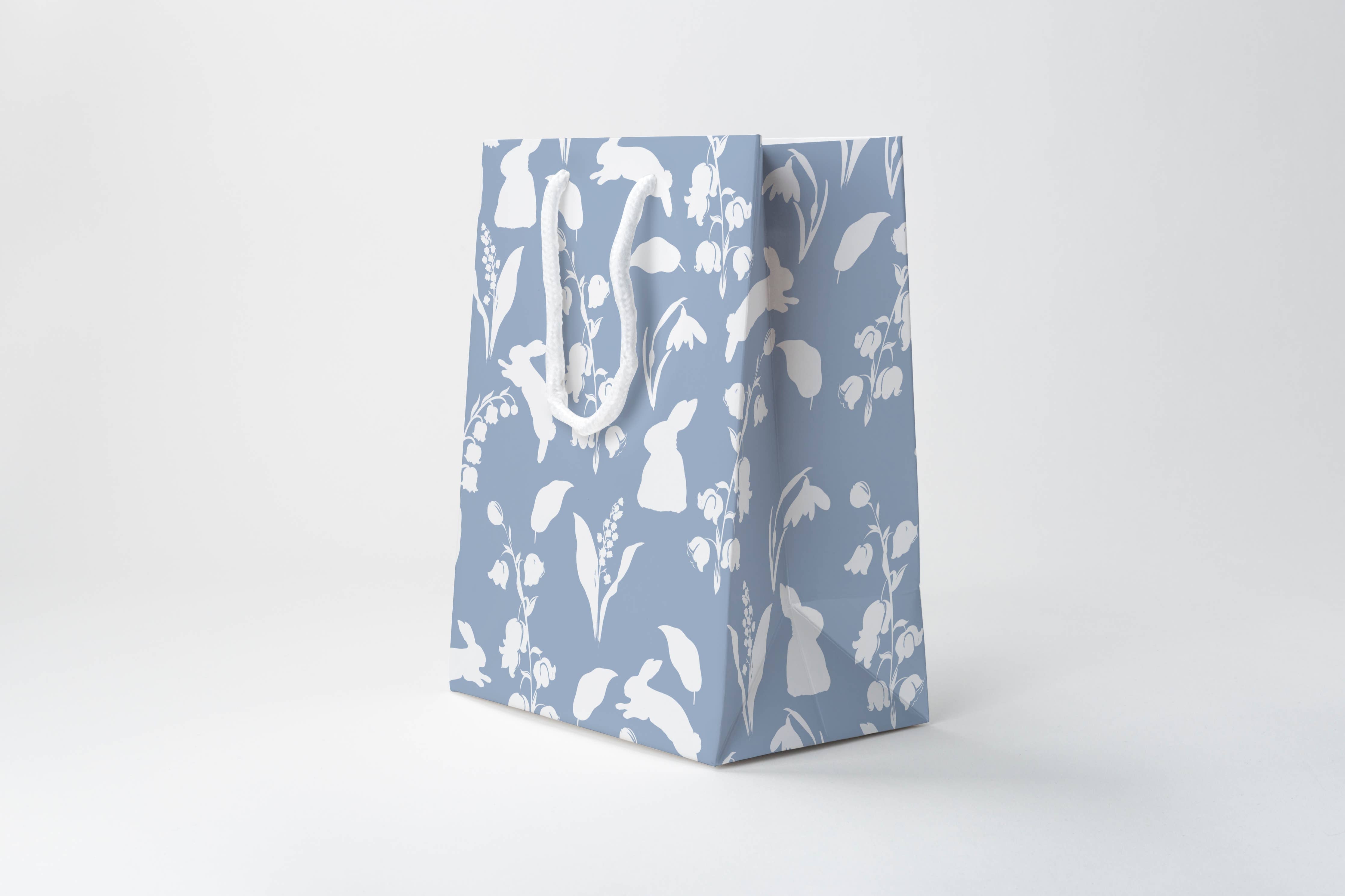 Blue paper bag with white floral and leaf pattern on a white background