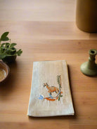 Embroidered towel with a fox design on a wooden surface