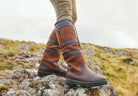 Brown insulated boots on a rocky landscape