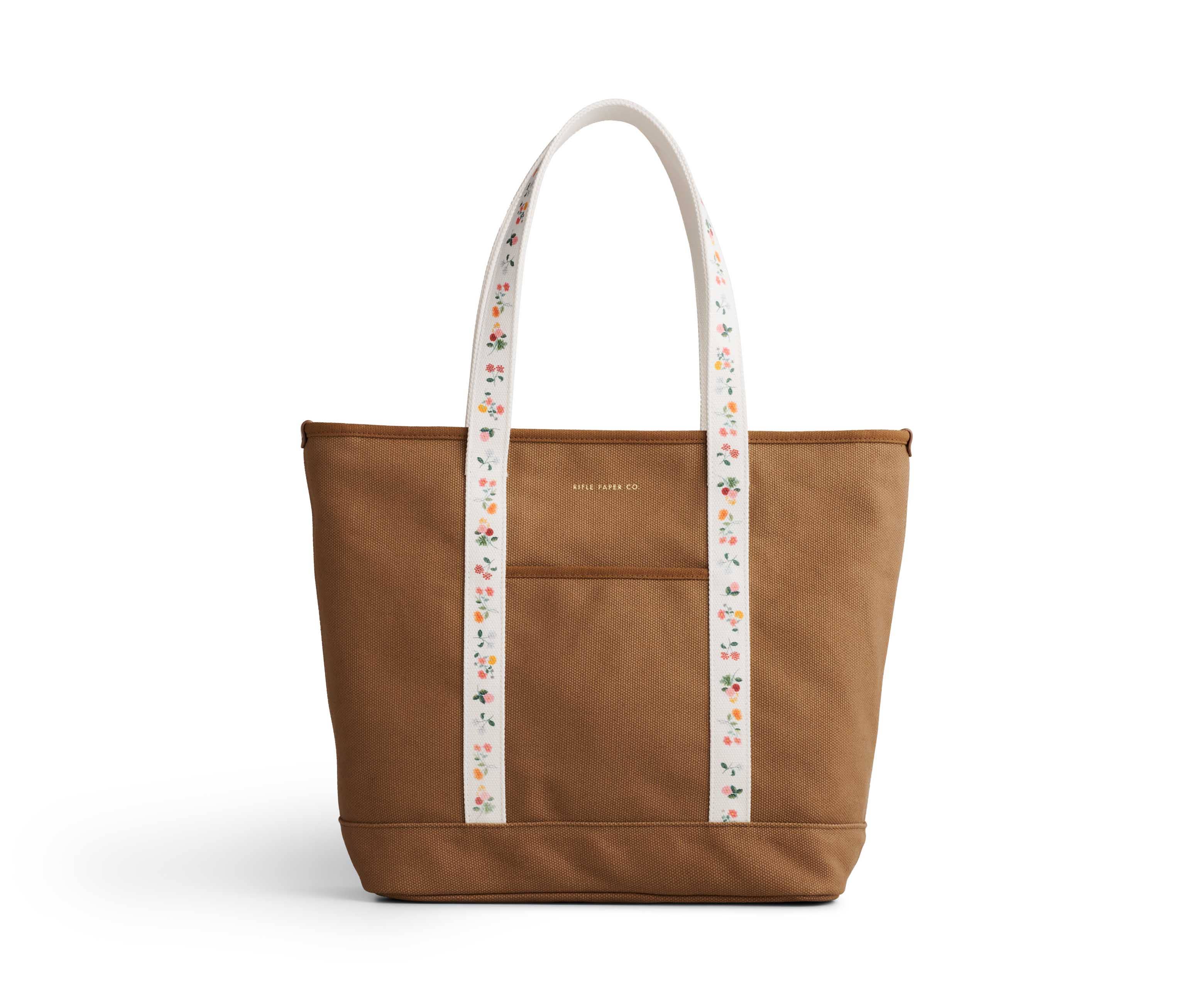 Brown tote bag with a floral-patterned strap on a white background