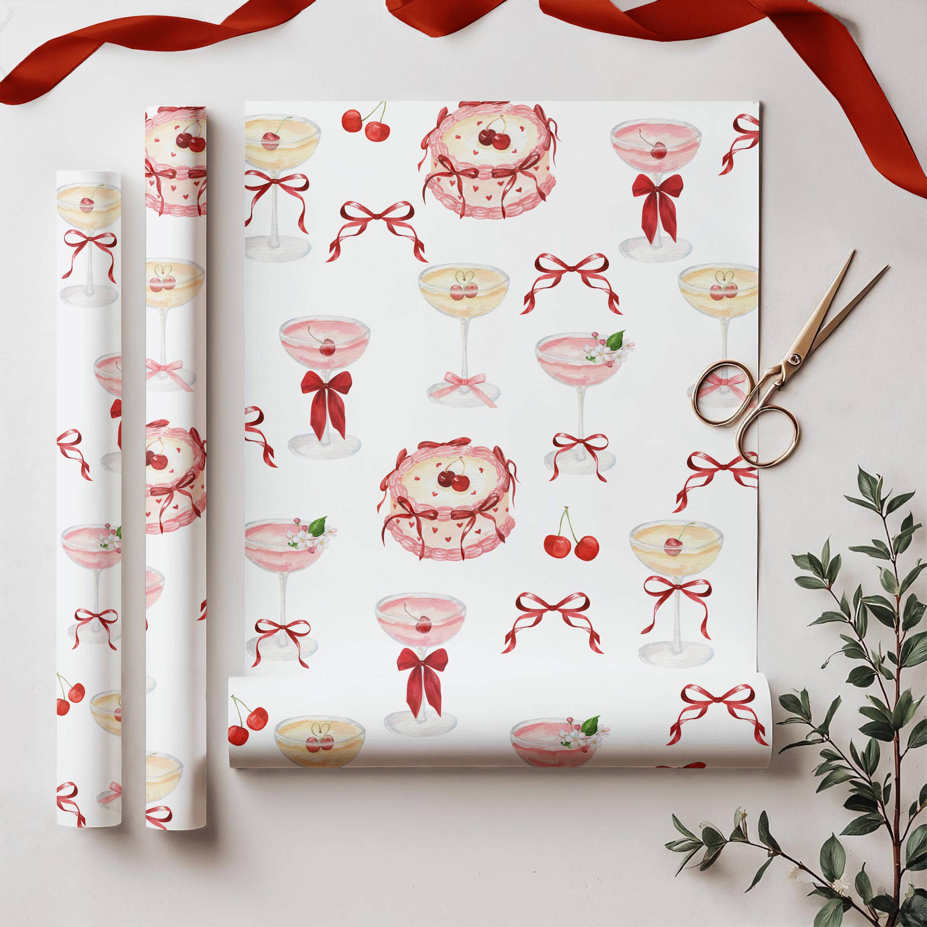 Roll of decorative paper with cocktail and bow pattern, scissors, and a plant on a light background