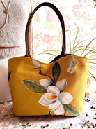 Yellow tote bag with floral design on a surface with a blurred background