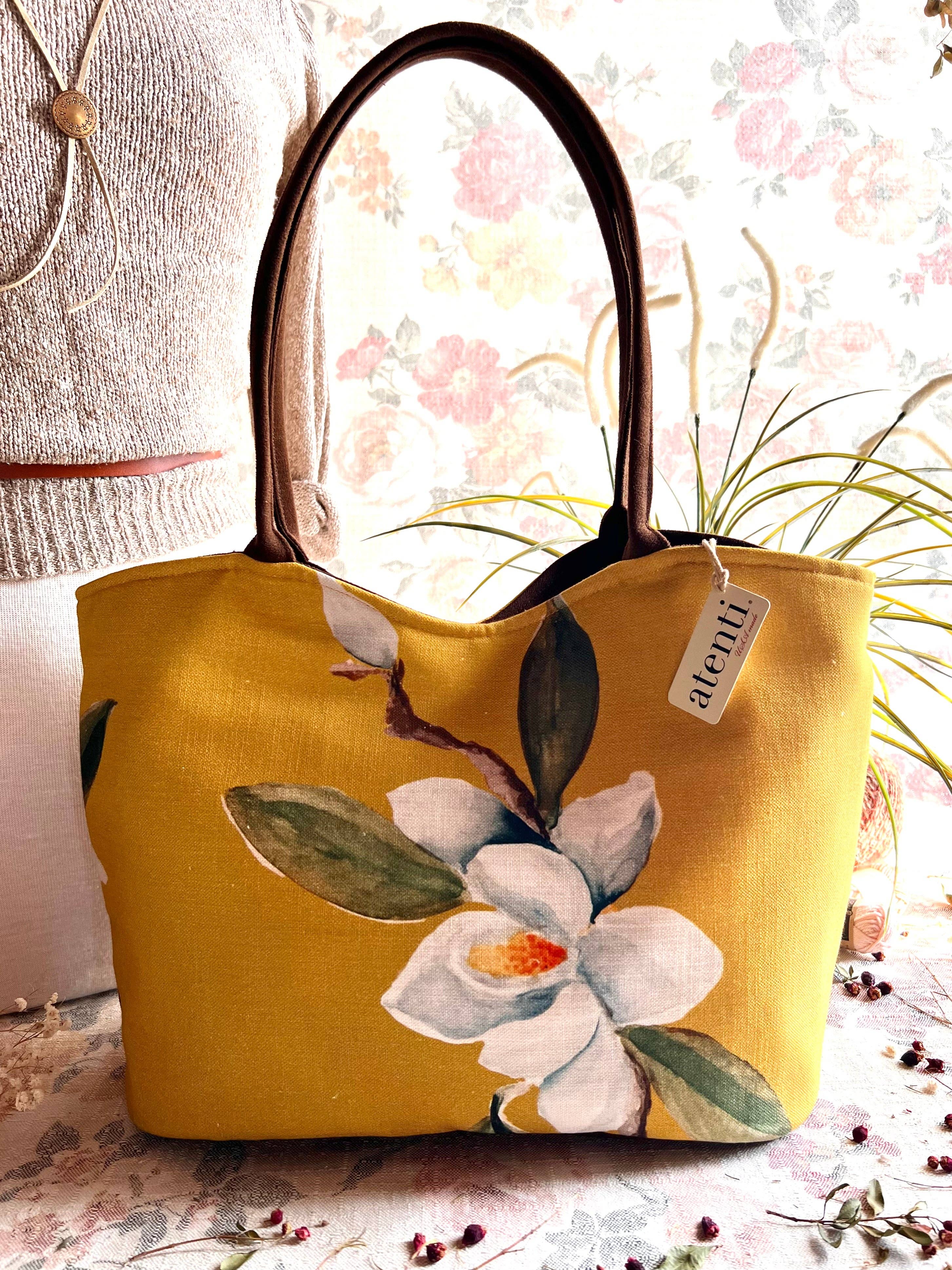 Yellow tote bag with floral design on a surface with a blurred background
