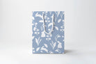 Gift bag with floral pattern and white handles on a light gray background