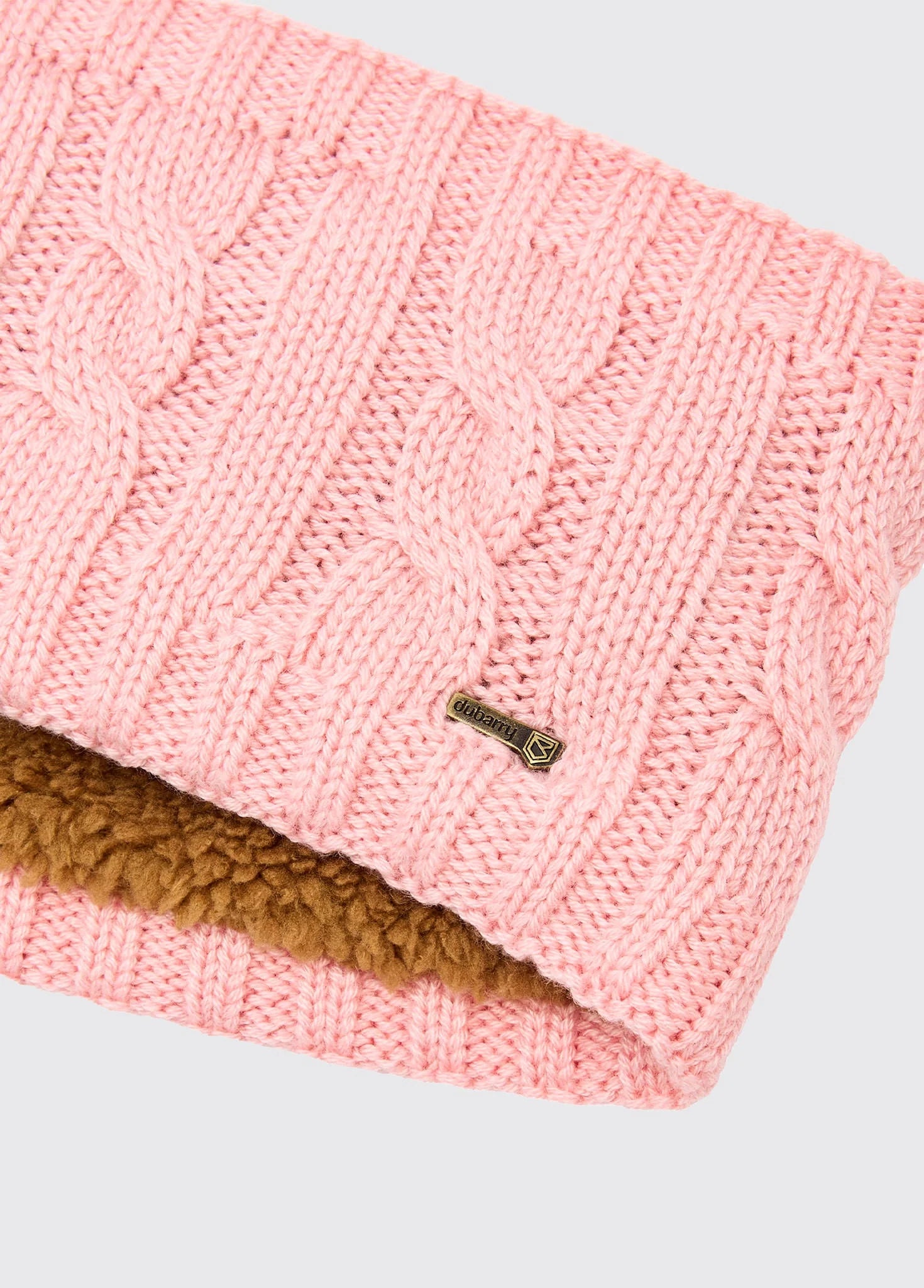 Pink knitted beanie with brown interior on a light gray background