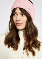 Woman wearing a pink knitted headband against a plain background