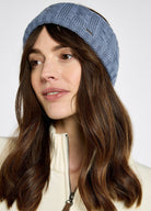 Woman wearing a blue knitted headband against a white background